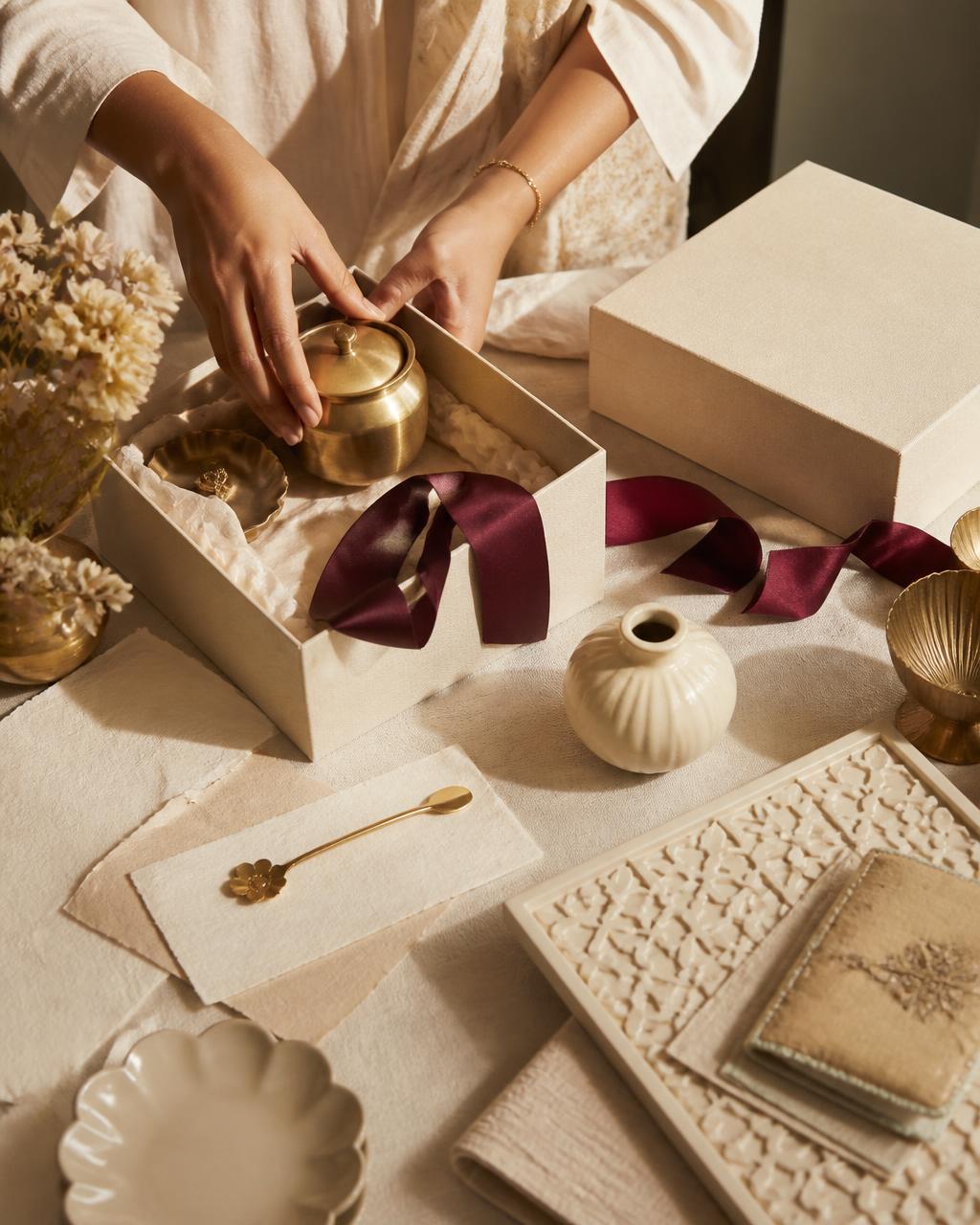 A curator arranging handcrafted objects in a gift box