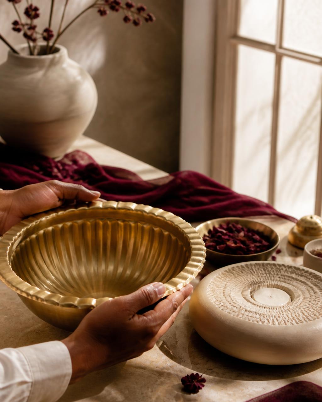 Hands examining a handcrafted brass urli
